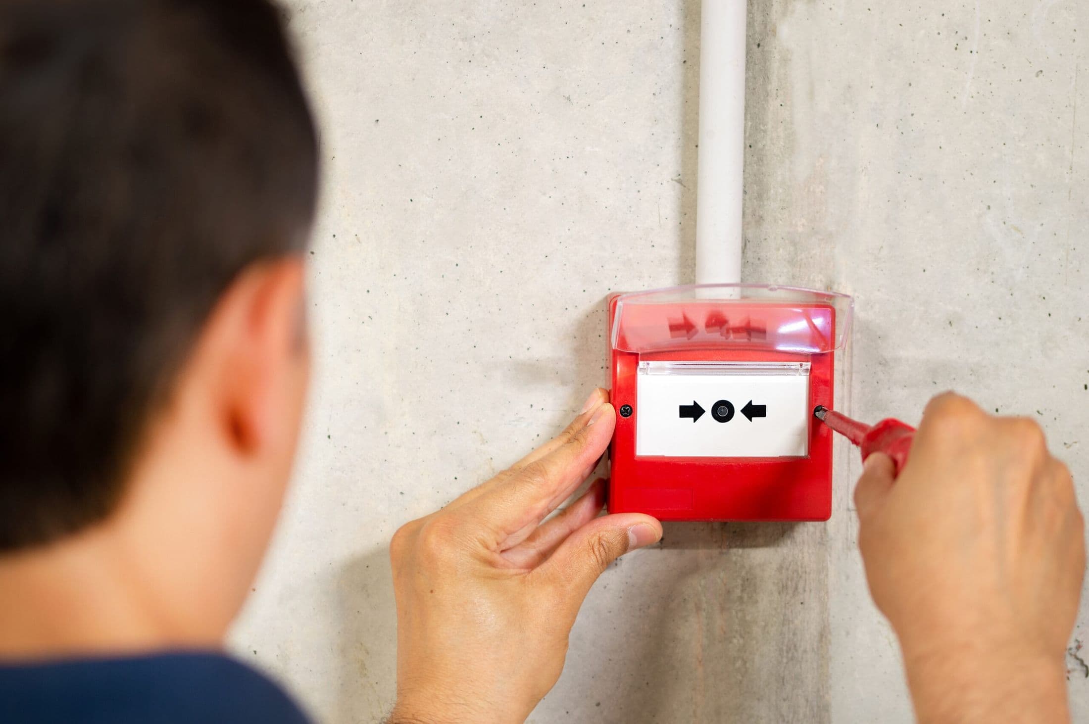 Engineer testing a fire alarm manual call point