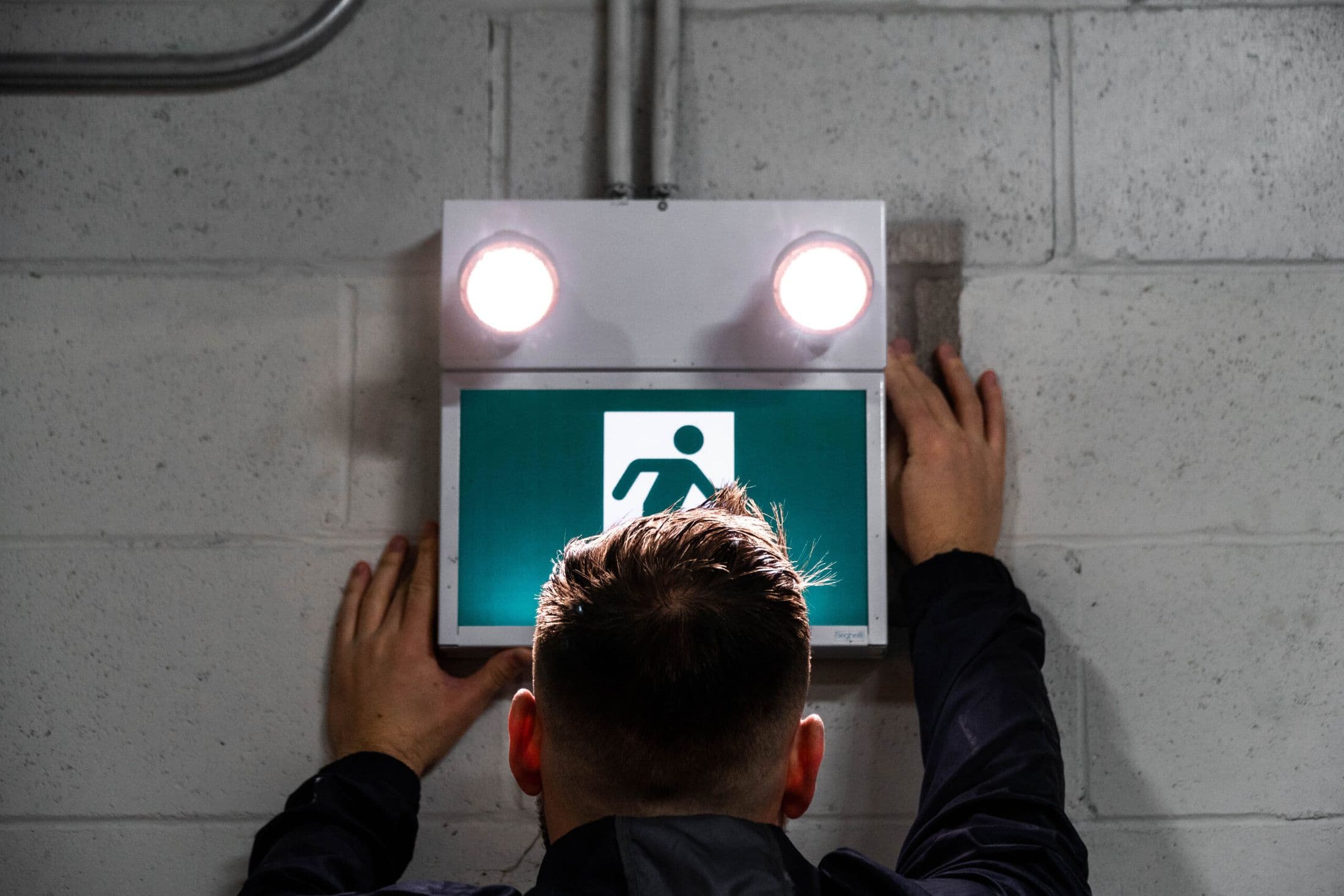 Engineer installing an illuminated emergency exit sign